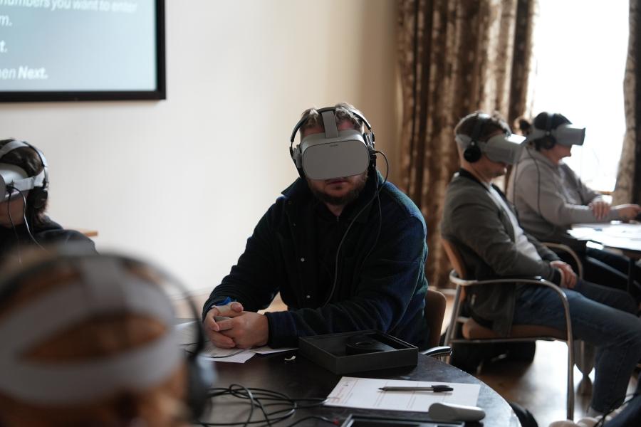 Unigolyn yn gwylio cyfres o senarios yn defnyddio penwisg VR